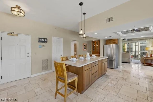 4361 Bay Beach Ln Unit 224, Fort Myers Beach, FL 33931 - kitchen with visible vents, freestanding refrigerator, stone tile floors, and brown cabinets