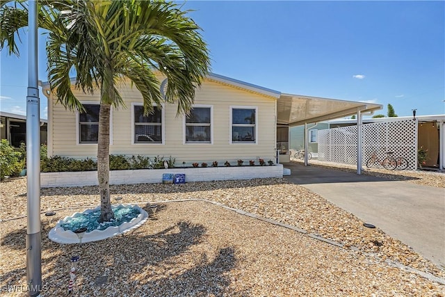 manufactured / mobile home featuring concrete driveway and an attached carport