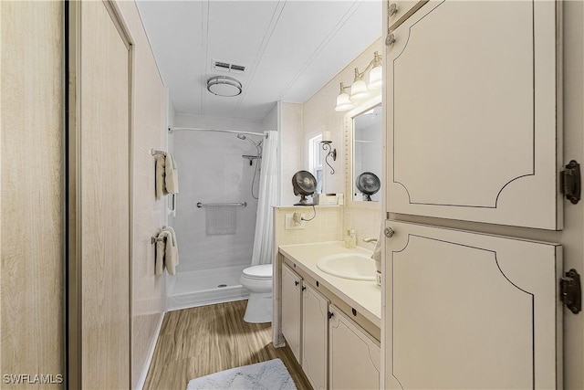 full bathroom with visible vents, toilet, vanity, wood finished floors, and a stall shower