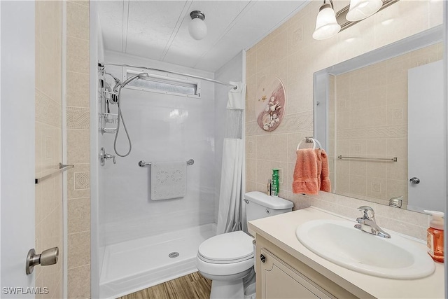 bathroom featuring toilet, tile walls, a stall shower, and vanity