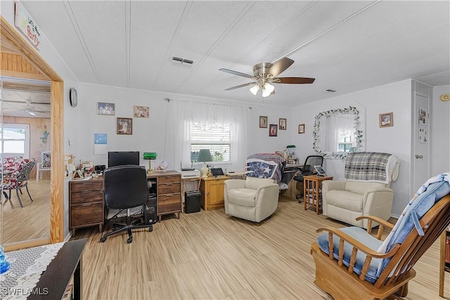 office with light wood finished floors, a ceiling fan, visible vents, and a wealth of natural light