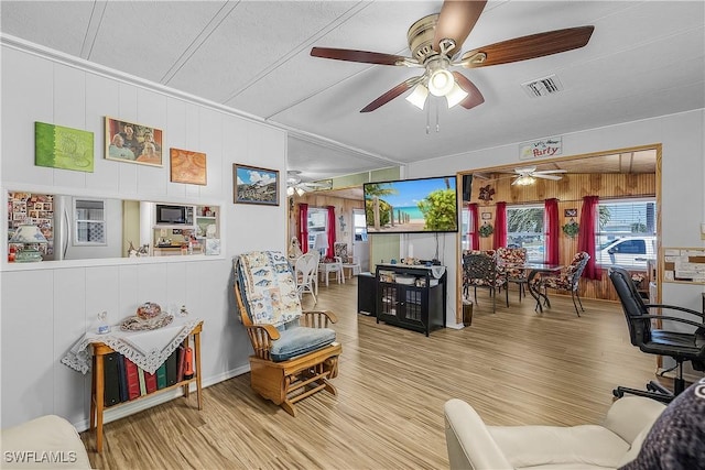 living area featuring visible vents, ceiling fan, wood finished floors, and wood walls