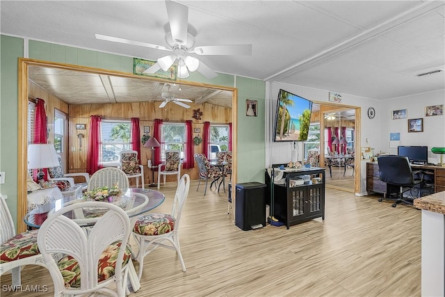 dining area featuring wood walls, visible vents, a ceiling fan, and light wood-style flooring