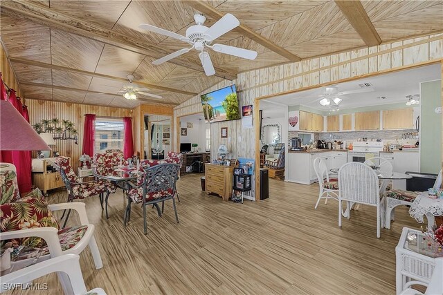 living area with wooden walls, light wood-type flooring, and a ceiling fan