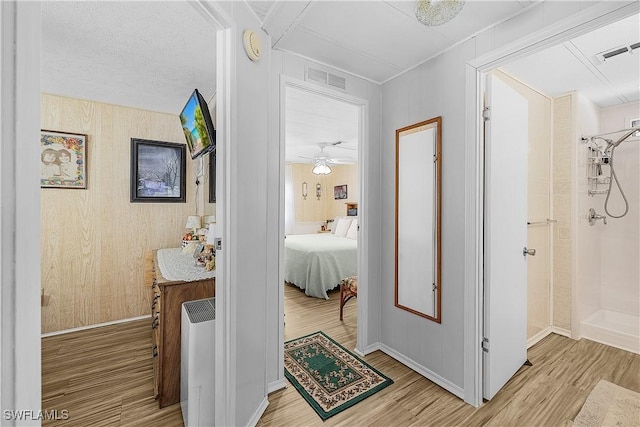 hallway with visible vents, light wood-style flooring, and baseboards