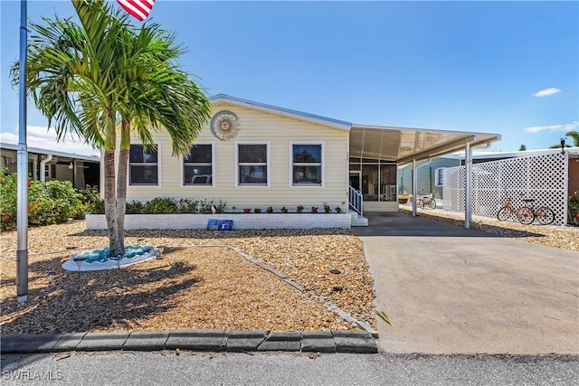 manufactured / mobile home featuring a sunroom, a carport, and driveway