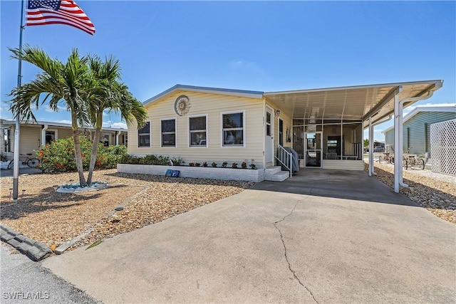 manufactured / mobile home with concrete driveway, a carport, and entry steps