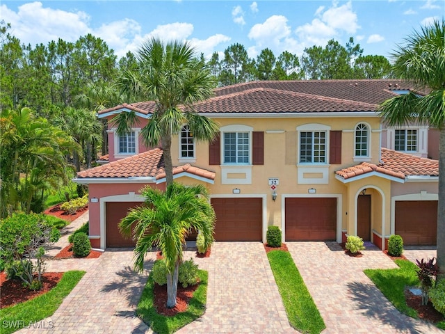 mediterranean / spanish home with driveway, a garage, stucco siding, and a tile roof