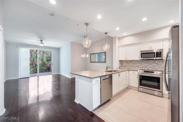 kitchen with white cabinetry, tasteful backsplash, a sink, stainless steel appliances, and open floor plan