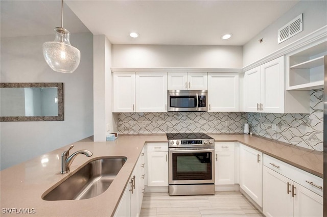 kitchen featuring a sink, stainless steel appliances, decorative backsplash, visible vents, and white cabinets