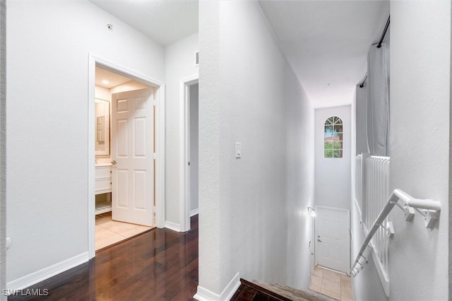 corridor featuring an upstairs landing, wood finished floors, and baseboards