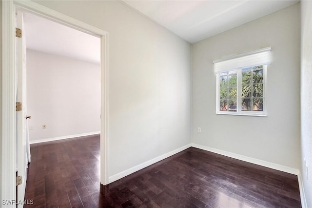 spare room with dark wood-type flooring and baseboards