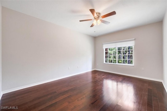 unfurnished room featuring dark wood-style flooring, ceiling fan, and baseboards