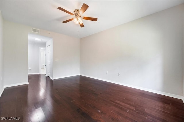empty room with dark wood-type flooring, visible vents, a ceiling fan, and baseboards