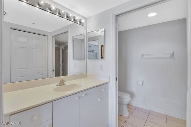 bathroom with baseboards, toilet, vanity, tile patterned flooring, and a shower with door
