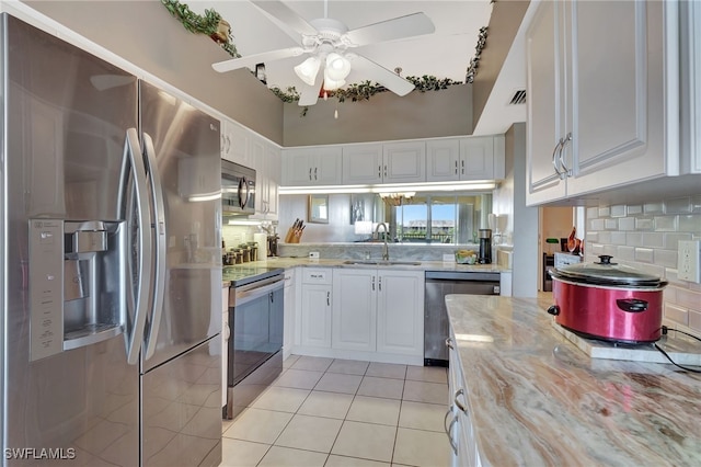 kitchen featuring white cabinets, light tile patterned flooring, a sink, stainless steel appliances, and decorative backsplash