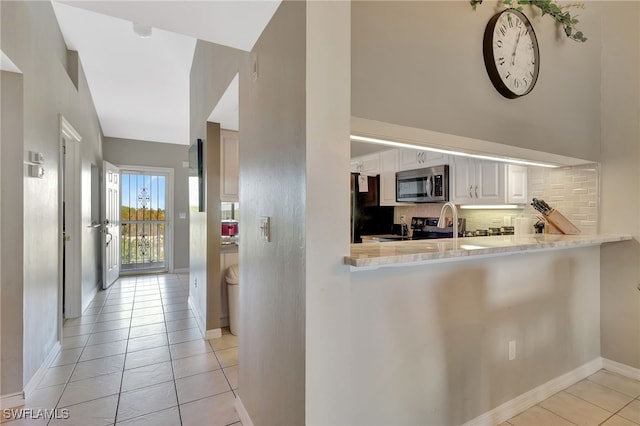 kitchen with baseboards, light countertops, appliances with stainless steel finishes, white cabinetry, and backsplash