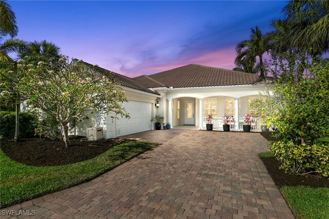 15384 Scrub Jay Ln, Bonita Springs, FL 34135 - mediterranean / spanish house with a tiled roof, covered porch, stucco siding, decorative driveway, and a garage