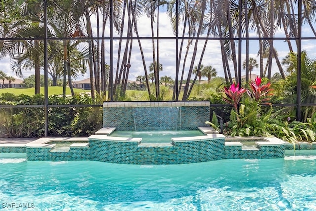 view of pool featuring a pool with connected hot tub and glass enclosure