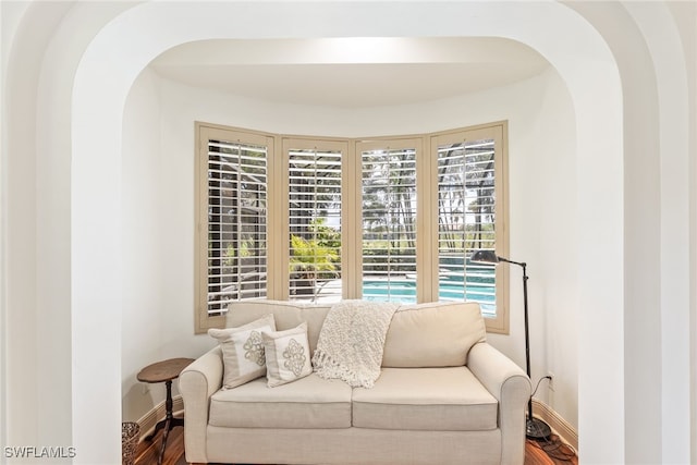 sitting room featuring arched walkways and baseboards