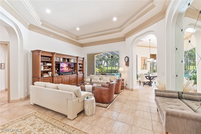 living area featuring baseboards, arched walkways, crown molding, a tray ceiling, and light tile patterned flooring