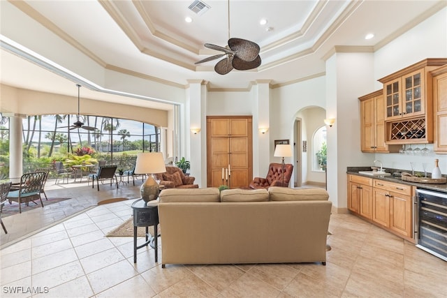living room featuring ceiling fan, arched walkways, wet bar, visible vents, and beverage cooler