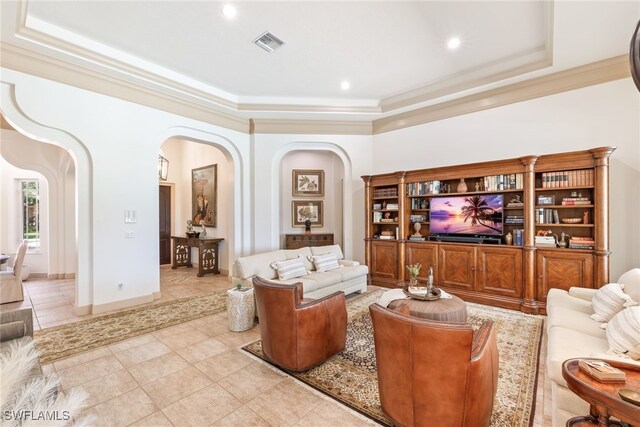 living area featuring arched walkways, visible vents, a tray ceiling, and ornamental molding