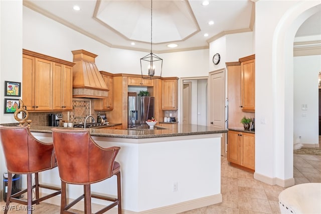 kitchen featuring stainless steel fridge with ice dispenser, recessed lighting, a peninsula, decorative backsplash, and a sink