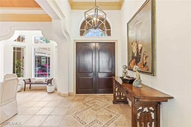 entrance foyer featuring baseboards, ornamental molding, a chandelier, a towering ceiling, and tile patterned flooring