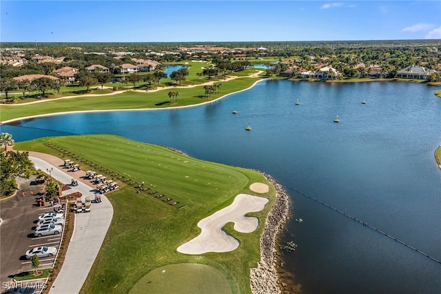 drone / aerial view with view of golf course, a residential view, and a water view