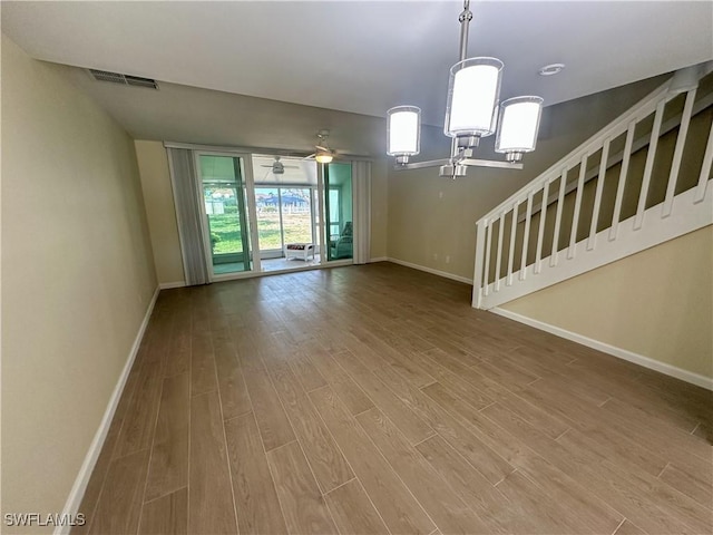 unfurnished living room featuring baseboards, wood finished floors, and visible vents