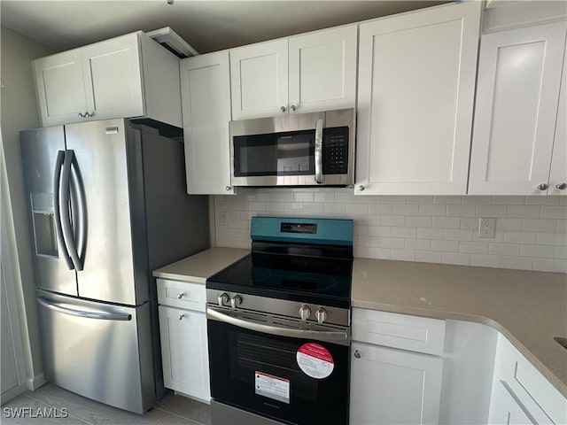 kitchen with white cabinets, appliances with stainless steel finishes, and decorative backsplash