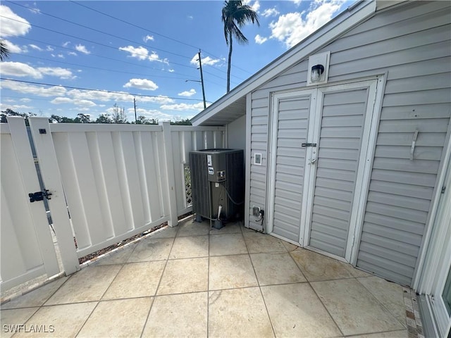 view of patio / terrace with fence, central AC unit, an outdoor structure, and a shed
