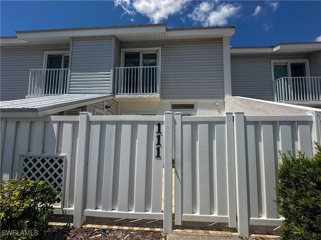 back of property with fence and a balcony
