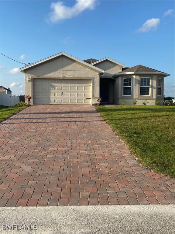 211 NE 20th St, Cape Coral, FL 33909 - ranch-style home featuring an attached garage, a front yard, stucco siding, and decorative driveway