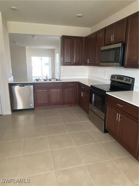 211 NE 20th St, Cape Coral, FL 33909 - kitchen featuring light tile patterned floors, light countertops, dark brown cabinets, appliances with stainless steel finishes, and a sink
