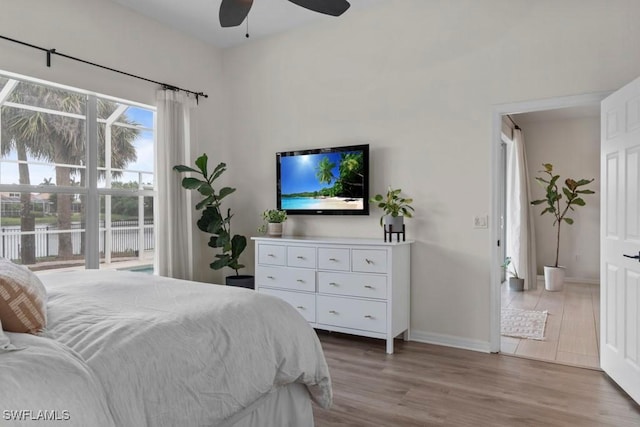 bedroom with wood finished floors, baseboards, a water view, a ceiling fan, and access to exterior