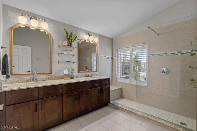 bathroom featuring lofted ceiling, a tile shower, double vanity, and tile patterned floors