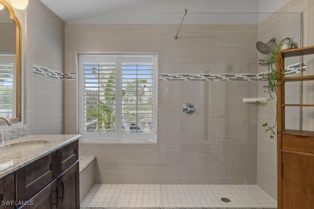 full bath featuring a tile shower, vaulted ceiling, and vanity