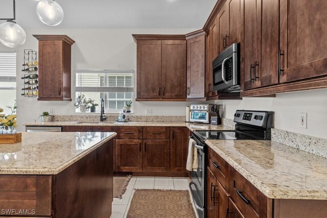 kitchen with appliances with stainless steel finishes, a sink, light stone counters, pendant lighting, and dark brown cabinets