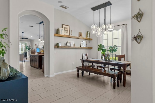 dining room with lofted ceiling, arched walkways, a chandelier, and baseboards