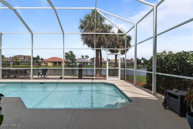 swimming pool with glass enclosure, a water view, and a patio area