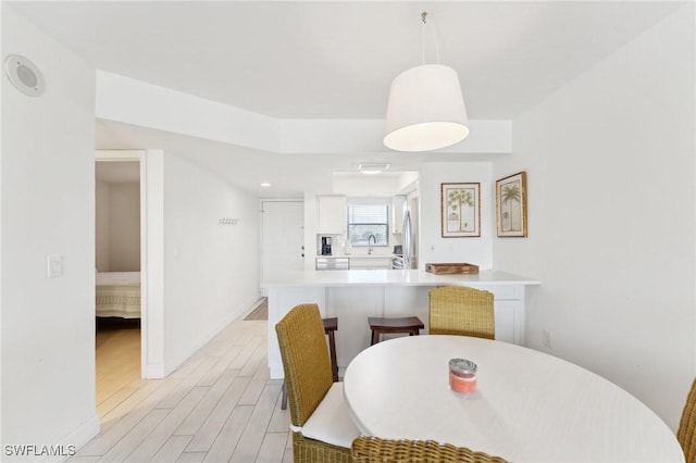 dining room featuring light wood finished floors and baseboards