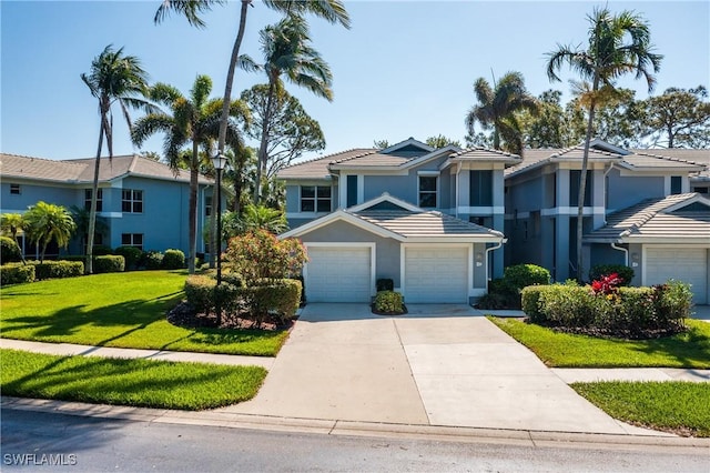 view of front of home with stucco siding, driveway, an attached garage, a front lawn, and a tiled roof