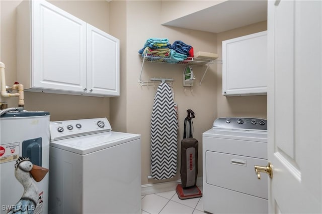 laundry room featuring water heater, baseboards, light tile patterned flooring, independent washer and dryer, and cabinet space