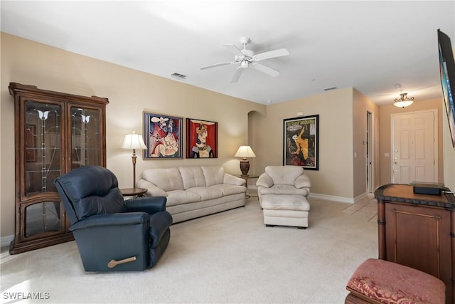 living area featuring visible vents, light colored carpet, baseboards, and ceiling fan