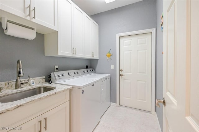 laundry area featuring baseboards, light tile patterned flooring, a sink, separate washer and dryer, and cabinet space