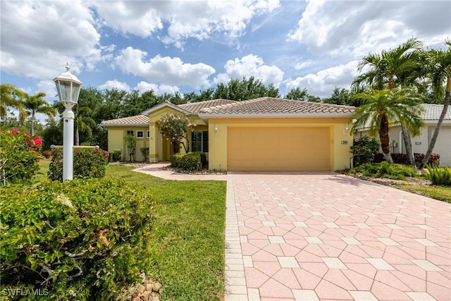 mediterranean / spanish-style home with stucco siding, a tiled roof, a garage, and decorative driveway