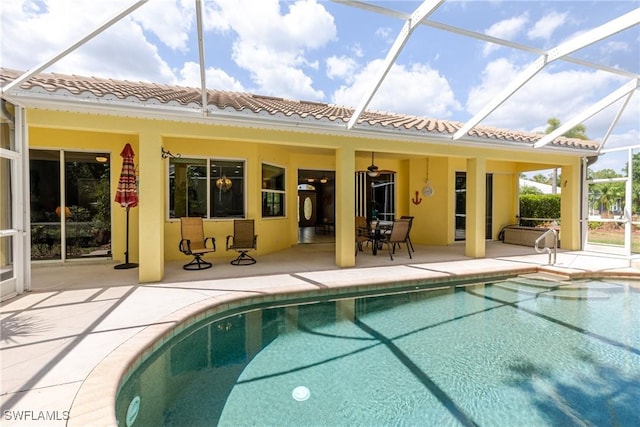 back of house with glass enclosure, an outdoor pool, a tile roof, a patio, and stucco siding