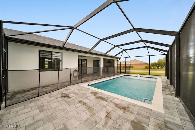 pool with ceiling fan, glass enclosure, and a patio